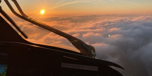 helicopter flying above the clouds at sunset